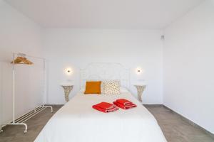 a white bed with two red pillows on it at Casa El Viaje in El Palmar +66 photos