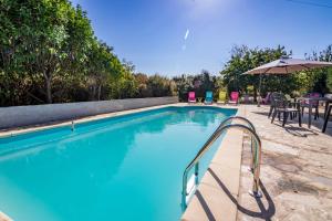 a swimming pool with an umbrella and tables and chairs at Chambre d'hôtes Au Chant des Vents in Thurageau