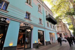 un edificio azul en una calle con gente caminando por la acera en Shota Rustaveli Aparthotel en Tiflis