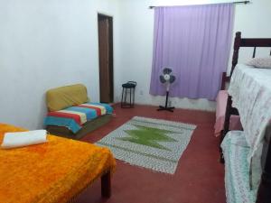 a room with two beds and a chair and a fan at Casas do Adriano in Conceição da Ibitipoca