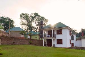 a white house with a green roof and a yard at Tooro Fairway Hotel in Fort Portal