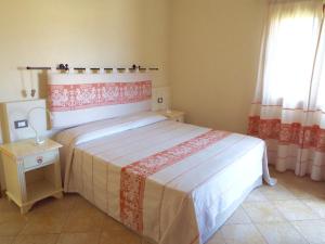 um quarto com uma cama com uma colcha vermelha e branca em Meravisola Costa Rei em Castiadas