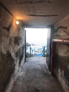 a tunnel with a door leading to the ocean at La Lampara Apartment in Aci Castello