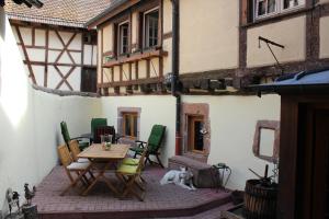 un patio con mesa, sillas y un perro en Les Gîtes Coeur de Vigne en Riquewihr