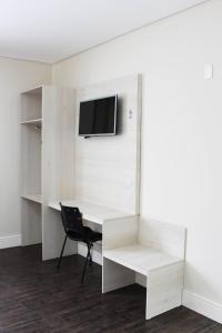 a white desk with a chair and a tv on a wall at CEIC Pousada e Eventos in Nova Trento
