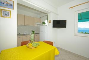 une cuisine avec une table et un chiffon de table jaune dans l'établissement Apartmani Maslina, à Gradac
