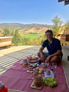 a man sitting on a picnic blanket with food at The Cave Of Wine by Casavino in Casablanca