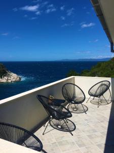 four chairs and a table on a balcony with the ocean at Apartments Kurelja in Lastovo