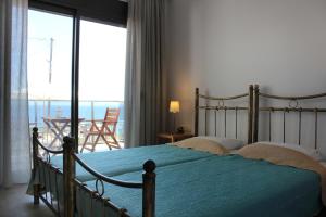 a bedroom with a bed and a balcony with a view at panorama studios in Afitos