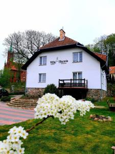een wit huis met bloemen ervoor bij B&B Villa Varmia in Frombork