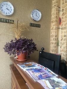 two clocks on the wall and a desk with a plant at Lara Hotel in Goris