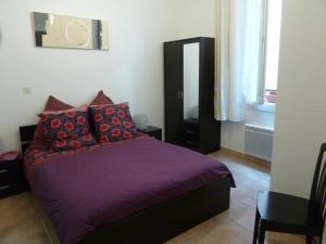 a bedroom with a purple bed with red pillows at 6 rue de la tourraque in Antibes