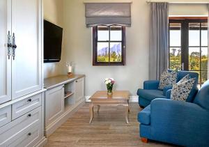 a living room with a blue couch and a tv at Huguenot House in Franschhoek