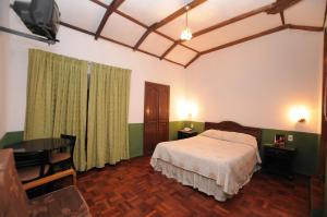 a bedroom with a bed and a desk and a television at Hostal Recoleta Sur in Sucre