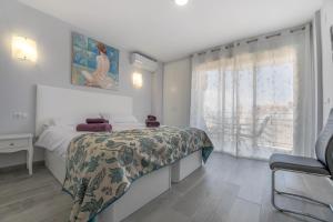 a white bedroom with a bed and a window at Precioso apartamento al lado de la playa in Benalmádena