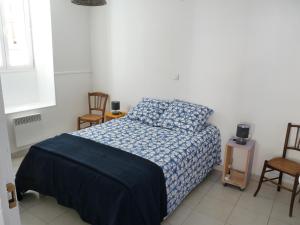 a bedroom with a bed with a blue blanket and two chairs at appartement de la callade in Peyriac-de-Mer