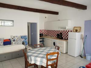 a kitchen with a table and a bed and a refrigerator at appartement de la callade in Peyriac-de-Mer