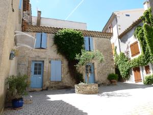 een oud stenen huis met blauwe deuren en bomen bij appartement de la callade in Peyriac-de-Mer