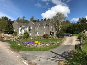 una casa en una carretera con flores en la entrada en Whitehill, en Finzean