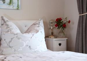 a bed with a pillow and a vase with red flowers at Ihre Auszeit am Golfplatz in Meisdorf