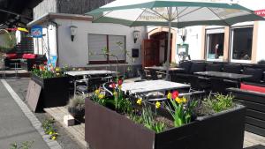 eine Terrasse mit Tischen, Stühlen und einem Sonnenschirm in der Unterkunft Pension Rodenburg in Duppach