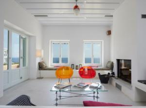 Sala de estar con 2 sillas de color naranja y mesa en Villa Rosa-Maria en Tinos Town