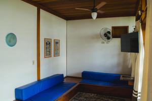 a living room with blue couches and a fan at Casa Inteira frente mar in Paraty