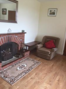 sala de estar con chimenea de ladrillo y silla en Foyleview Cottage, Moville en Moville