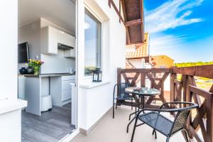 a balcony with a table and chairs and a kitchen at Apartament Monia in Sztutowo