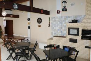 a restaurant with tables and chairs and a fireplace at Enseada Hostel in Arraial do Cabo