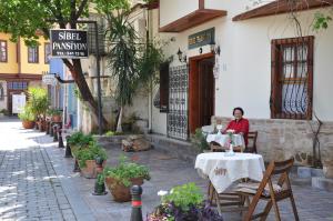una mujer sentada en una mesa frente a un edificio en Sibel Hotel en Antalya