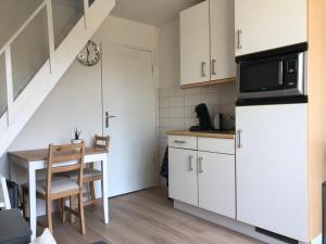 a kitchen with white cabinets and a table with a microwave at Logies het Noordwestertje in Den Burg