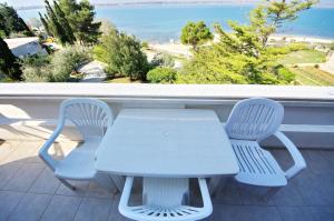 uma mesa branca e duas cadeiras numa varanda com o oceano em Apartments Beach em Vrsi