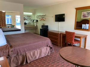 ein Hotelzimmer mit einem Bett, einem Schreibtisch und einem Tisch in der Unterkunft Royal Regency Inn in Rock Hill