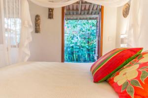 a bedroom with a bed with two pillows and a window at Suíte Charmosinha in Caraíva