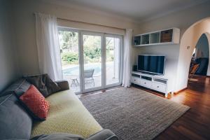 a living room with a couch and a television at Sunny Soul in Malveira da Serra