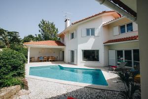 a villa with a swimming pool in front of a house at Sunny Soul in Malveira da Serra