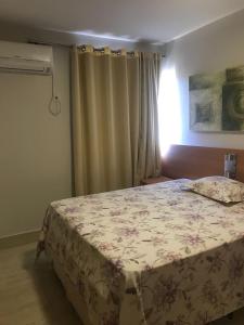 um quarto com uma cama grande e uma colcha floral em Thermas Paradise Cobertura de Alto Padrão em Rio Quente