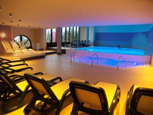 einen Pool in einem Raum mit Stühlen davor in der Unterkunft Kurhotel zu Heringsdorf in Heringsdorf