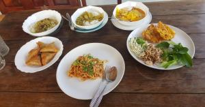 a wooden table with plates of food on it at Sweetville Home in Sangkhla Buri