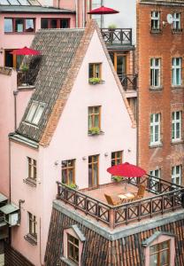 a house with a balcony with tables and umbrellas at Vincent Restauracja&Apartamenty in Wrocław