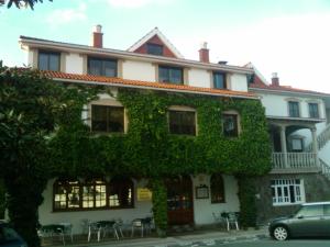 a building covered in green ivy with a car parked in front at Hotel O Castelo in Cervo