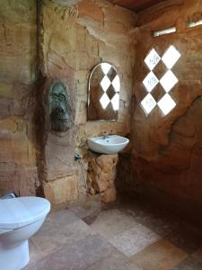 a stone bathroom with a sink and a statue at On The Rocks Bungalows, Restaurant and Jungle Trekking Tours in Bukit Lawang
