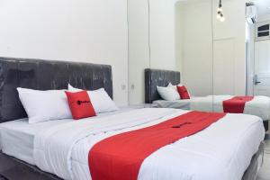 - une chambre avec 2 lits dotés d'oreillers rouges et blancs dans l'établissement RedDoorz Plus @ Kemayoran, à Jakarta