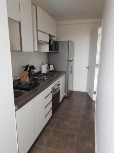 a kitchen with white cabinets and a sink and a refrigerator at Condominio Alto Hacienda - Coquimbo in Coquimbo