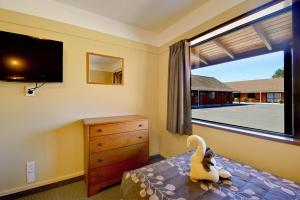 a bedroom with a bed and a large window at Mosgiel Regency Motel in Mosgiel