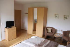 a room with a bed and a cabinet with a television at Pension Fischer in Bad Driburg