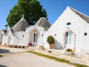 un edificio blanco con 2 techos de paja y flores en Agriturismo Masseria Aprile, en Locorotondo