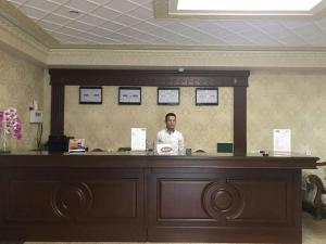 a man standing behind a counter in a room at Hotel Afrosiyob in Qarshi