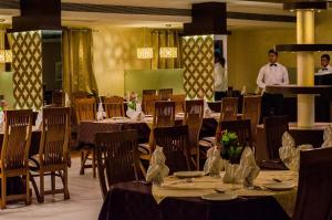 un comedor con mesas y sillas con personas en el fondo en Hotel Sheela Shree Plaza, en v